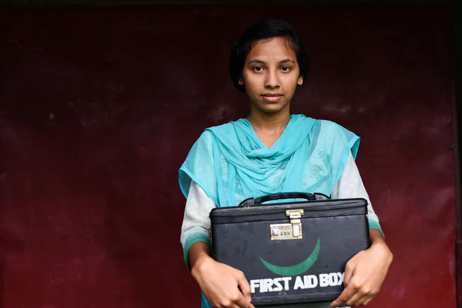 A teenage girl holds a medical kit