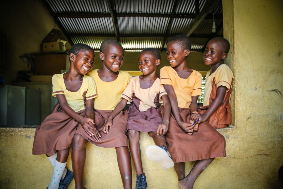 smiling girls wearing matching yellow shirts and brown skirts