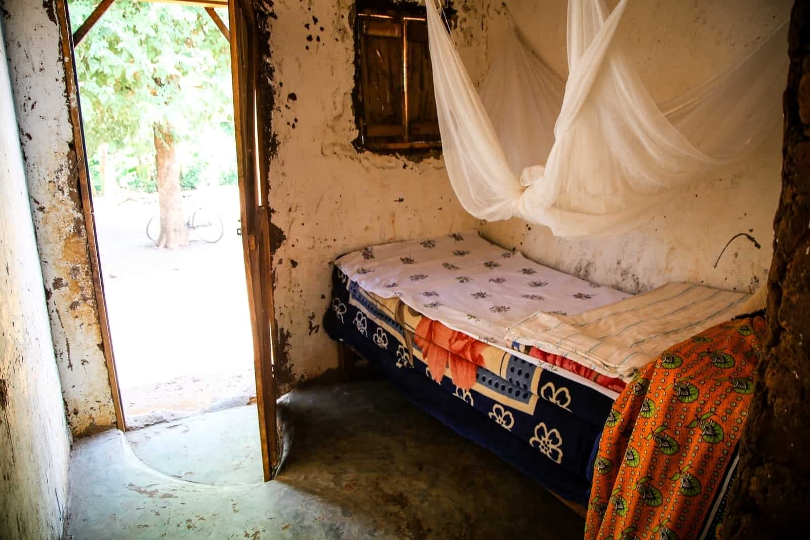 A small bedroom with a bed with a mosquito net over it.