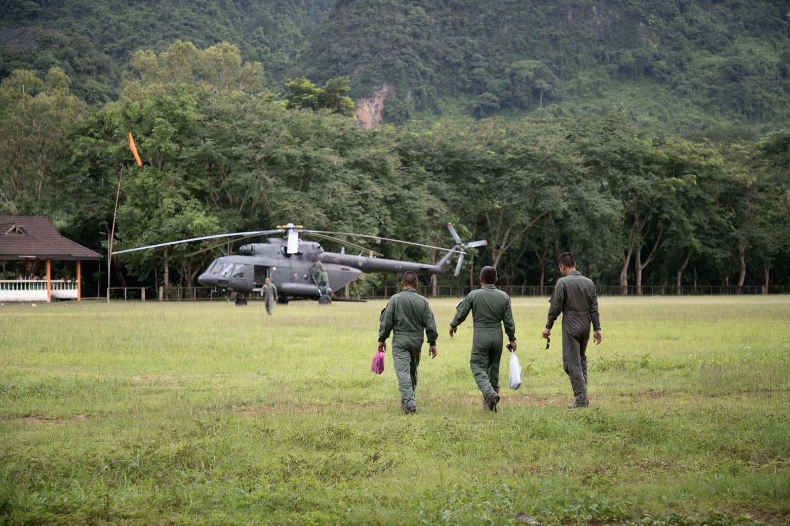 three military men walking towards helicopter