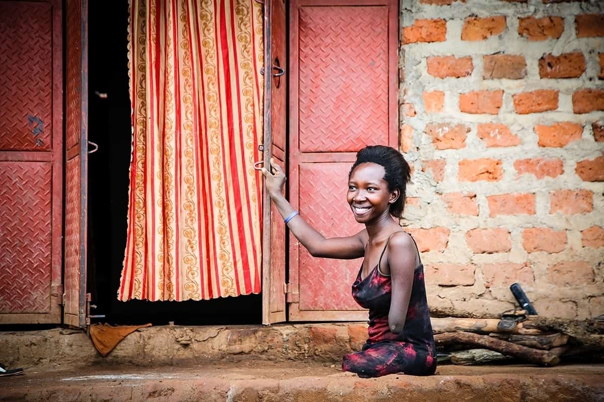 Grace is seen smiling outside her home in Uganda.