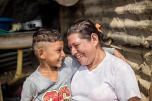 A woman stands smiling with her son in their kitchen where they have been feeding people fleeing Venezuela's economic crisis