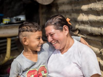A woman stands smiling with her son in their kitchen where they have been feeding people fleeing Venezuela's economic crisis