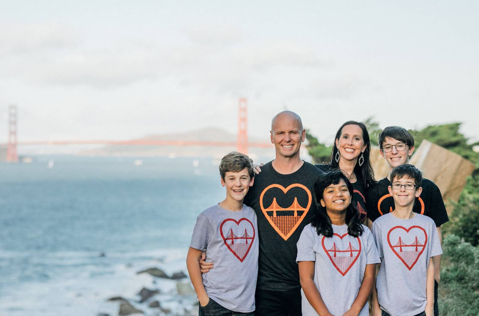 A man and woman and four children stand in front of the Golden Gate Bridge, wearing T-shirts with a graphic of the Golden Gate Bridge on it.