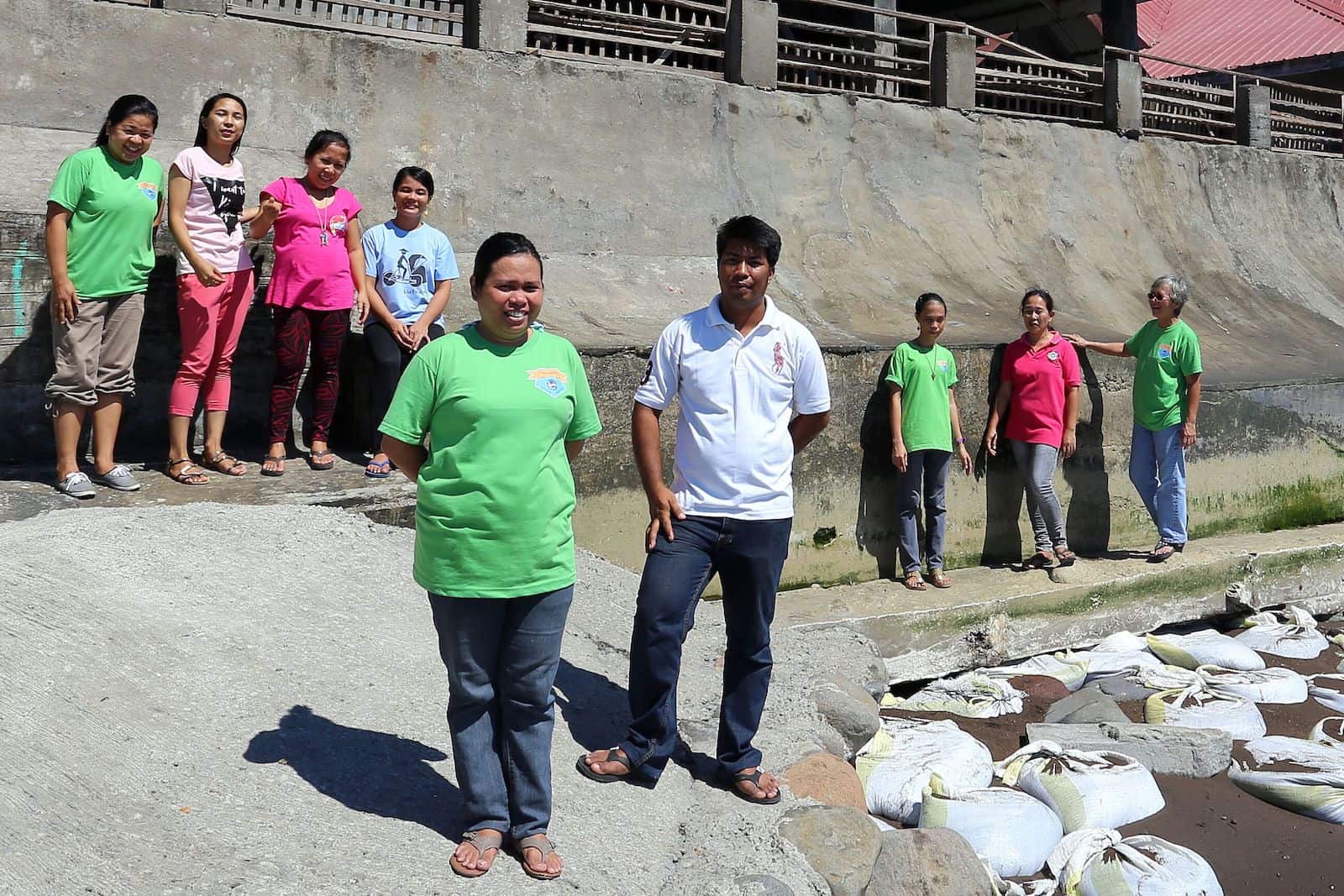 A group of people stand outside a concrete church building, wearing jeans and T-shirts. 