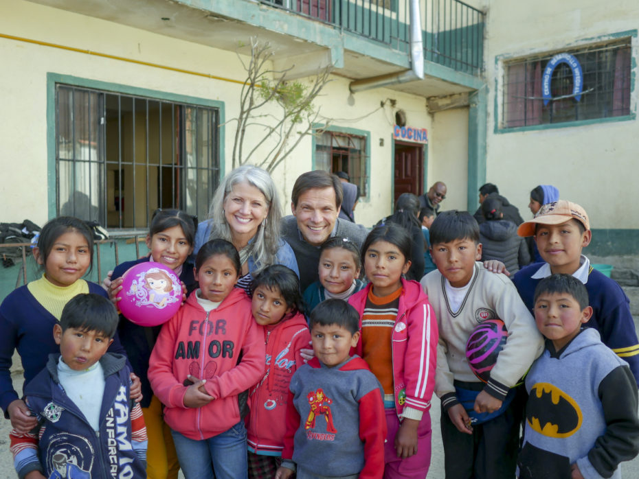 Two people, Jimmy and Leanne Mellado, pose for a group photo with a group of children in Bolivia.