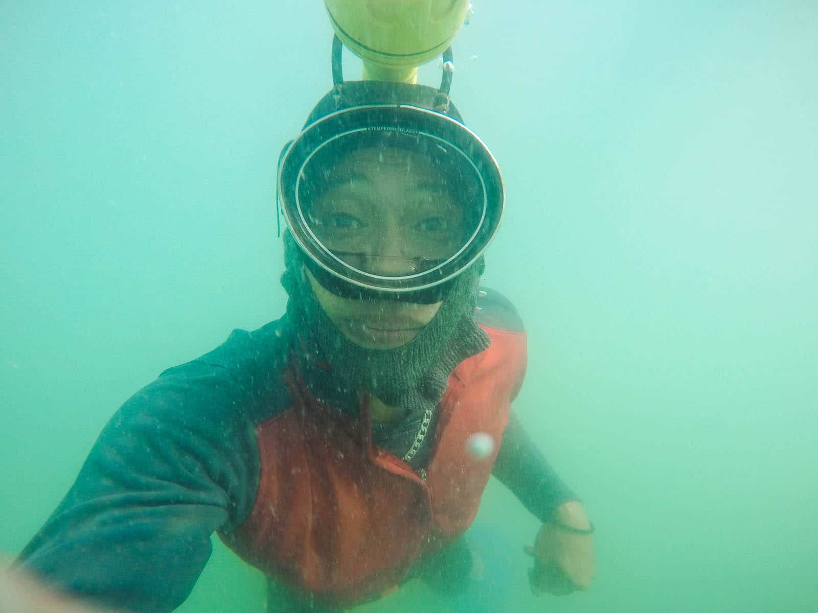 A man underwater, wearing a swim mask and a flashlight strapped to his head.