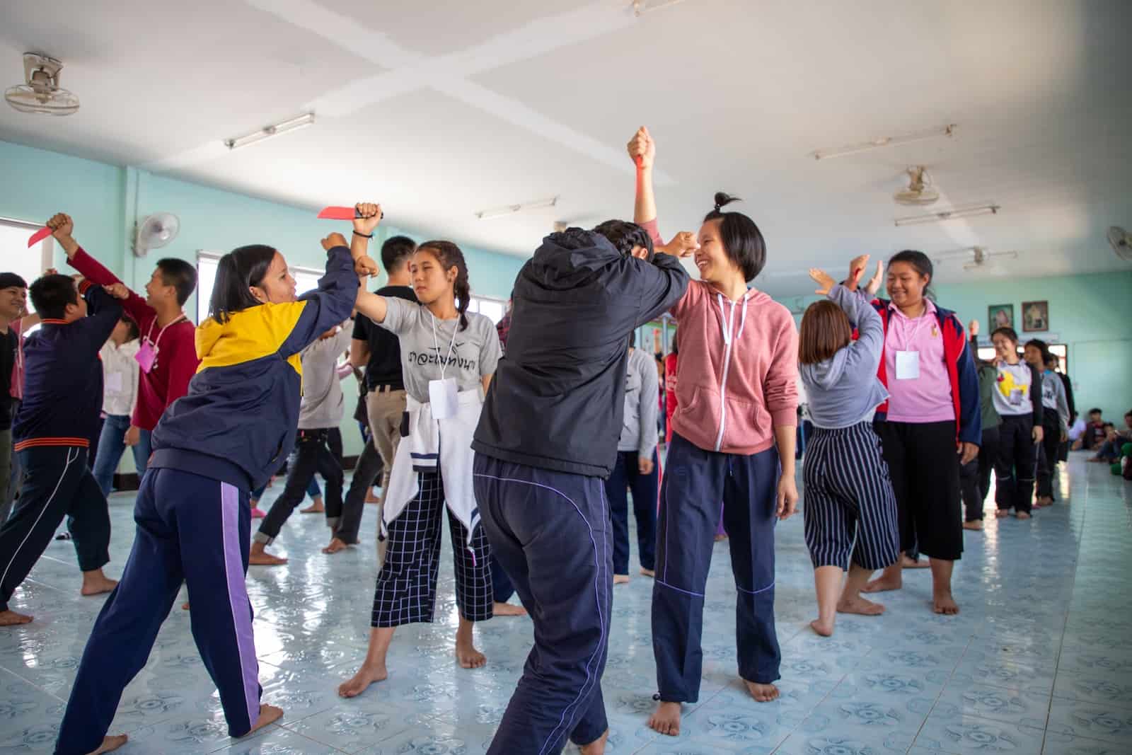 A group of girls stands in a classroom, practicing self-defense techniques to prevent child sexual abuse. 