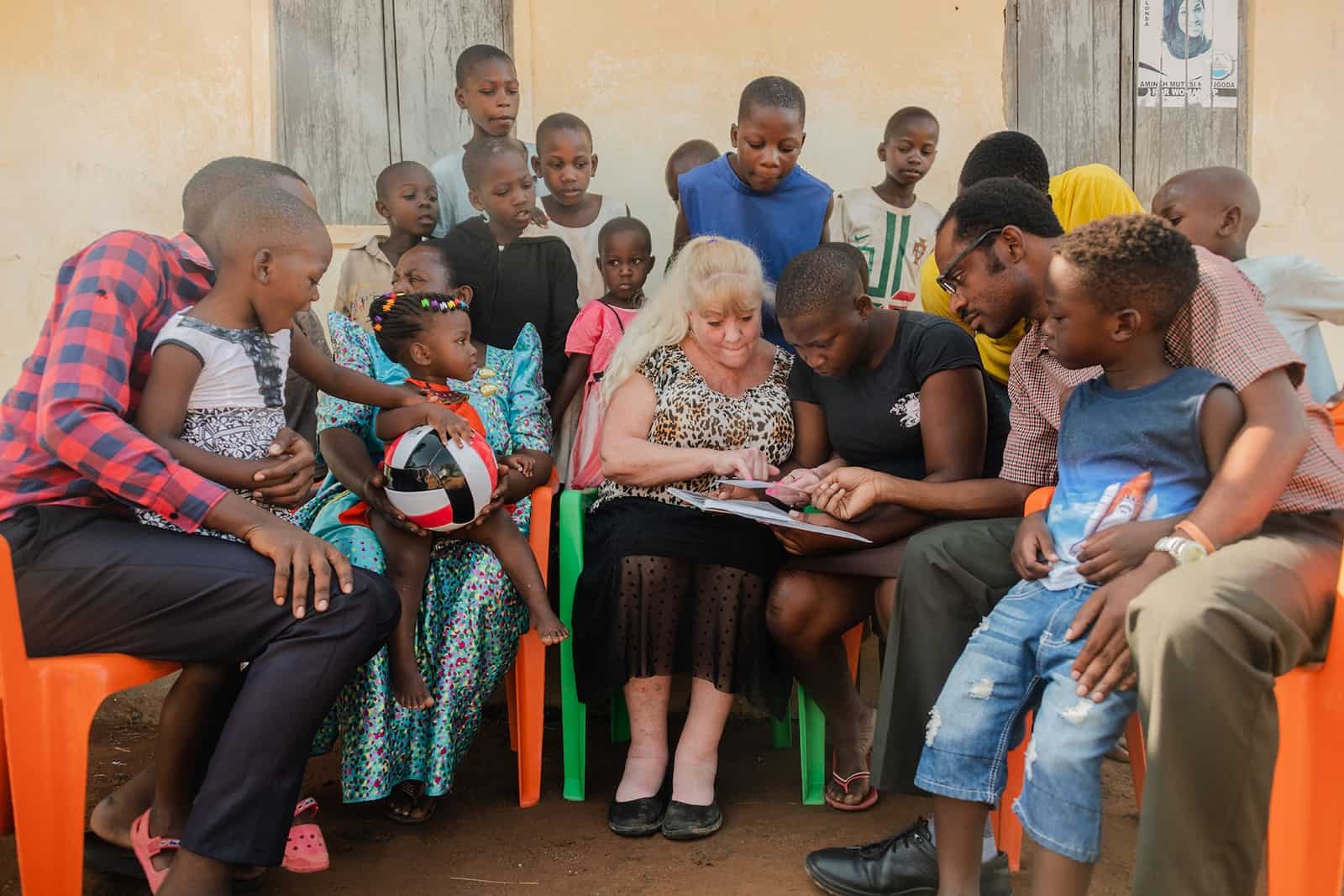 A woman sits down with a young woman and looks through a photo album, surrounded by a large family including her namesakes.