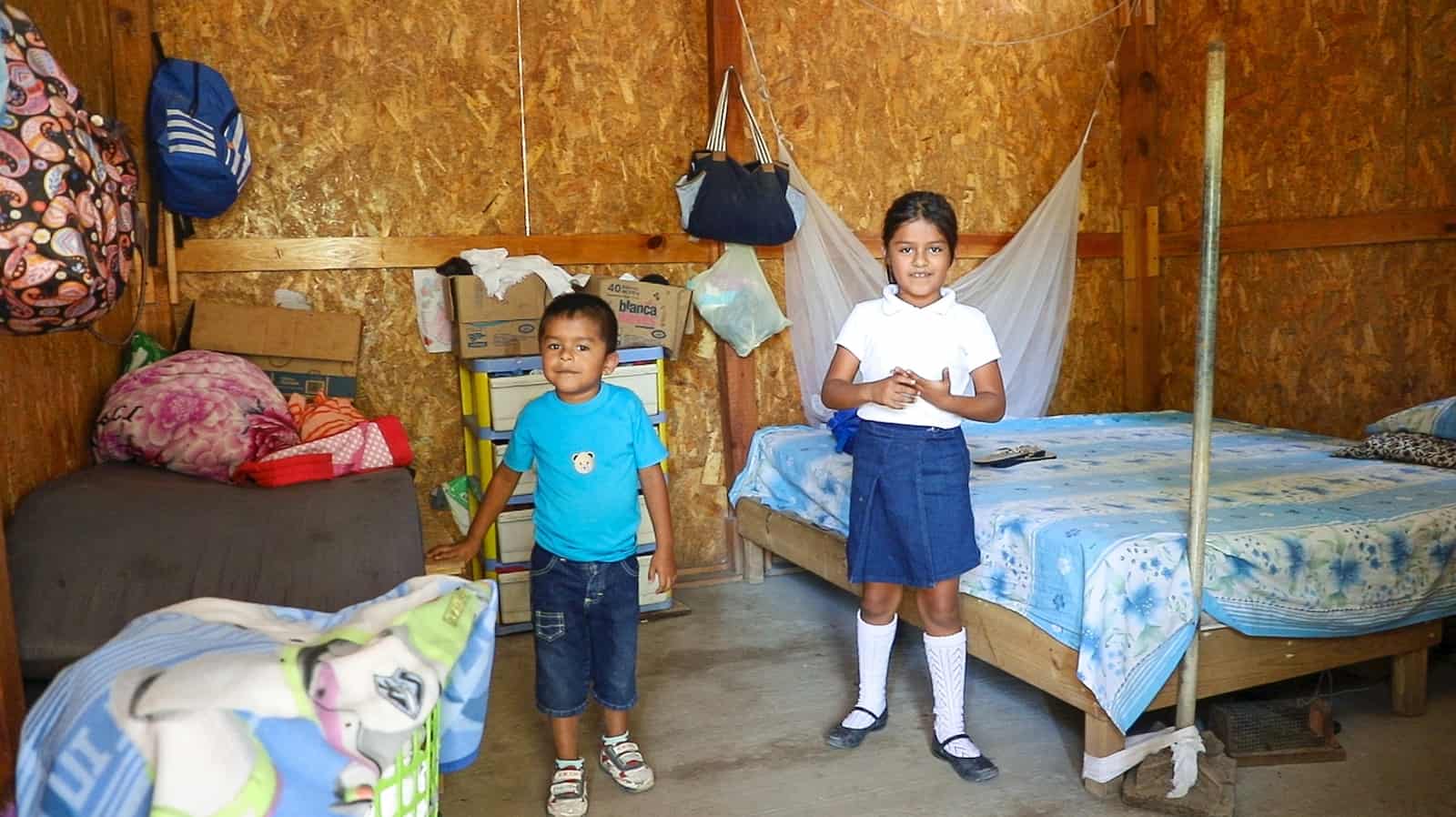A boy and girl stand inside a home rebuilt after the Mexico earthquake next to their beds. 
