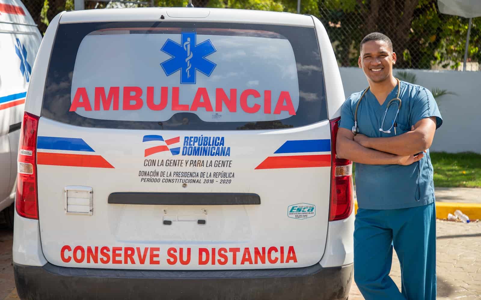 A man leans against an ambulance van.