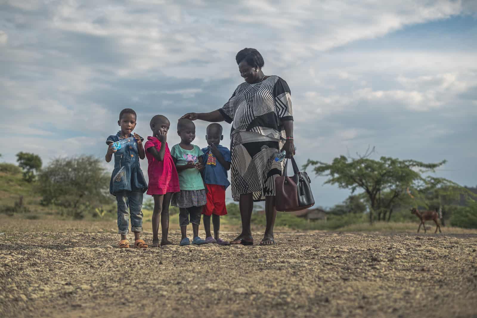 A woman stands next to four little girls. 