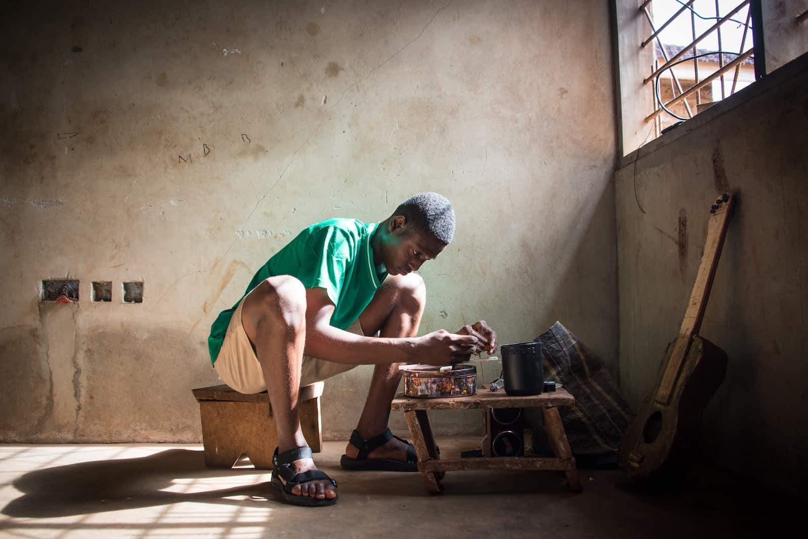 A young boy sits nexts to a table, tinkering with objects.