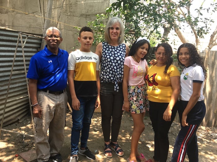 A woman and man stand outside with four youth around them.