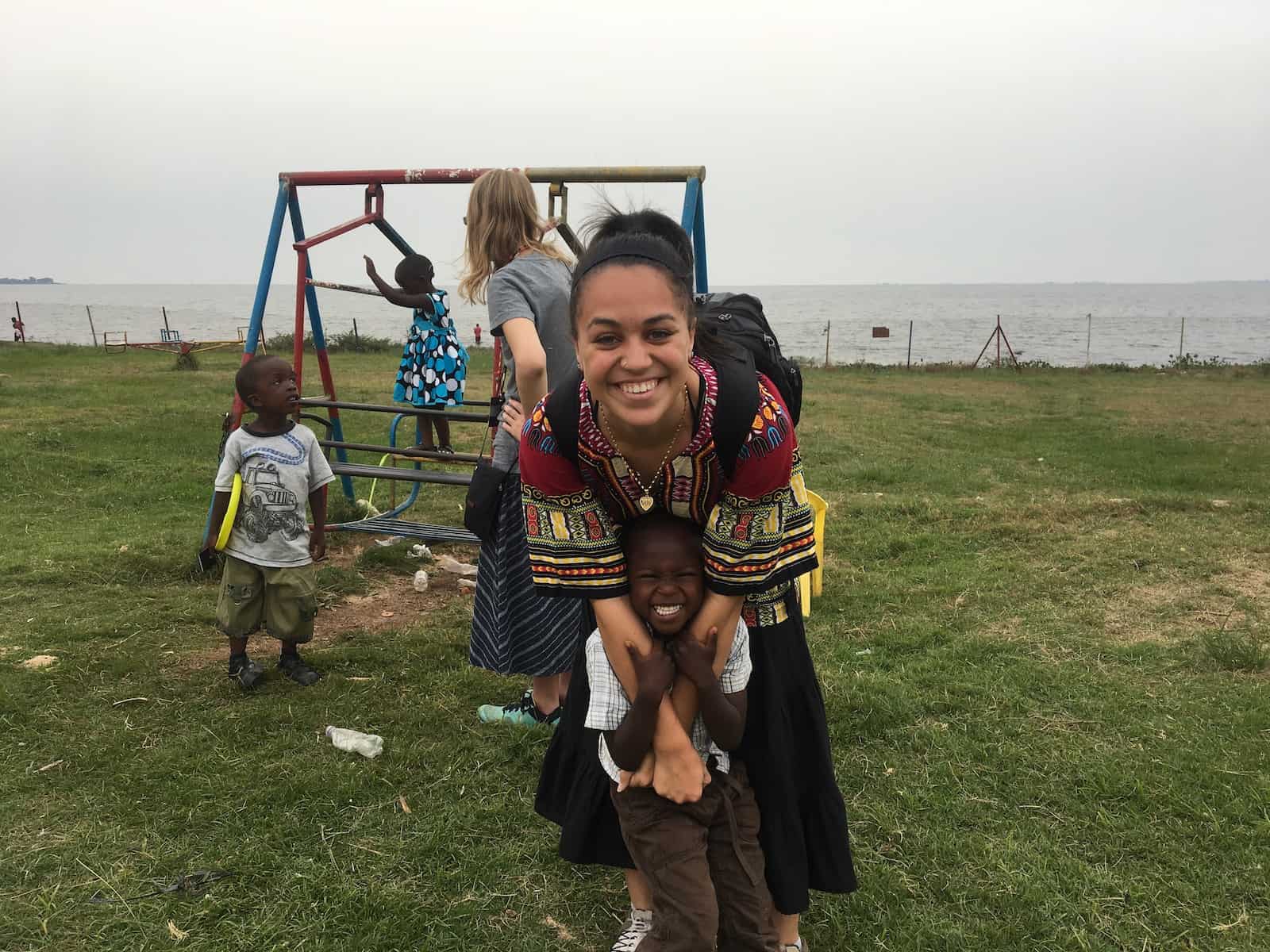 A woman hugs a small boy in front of a swing set. 