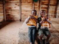 Two boys in Uganda hug Christmas gifts.