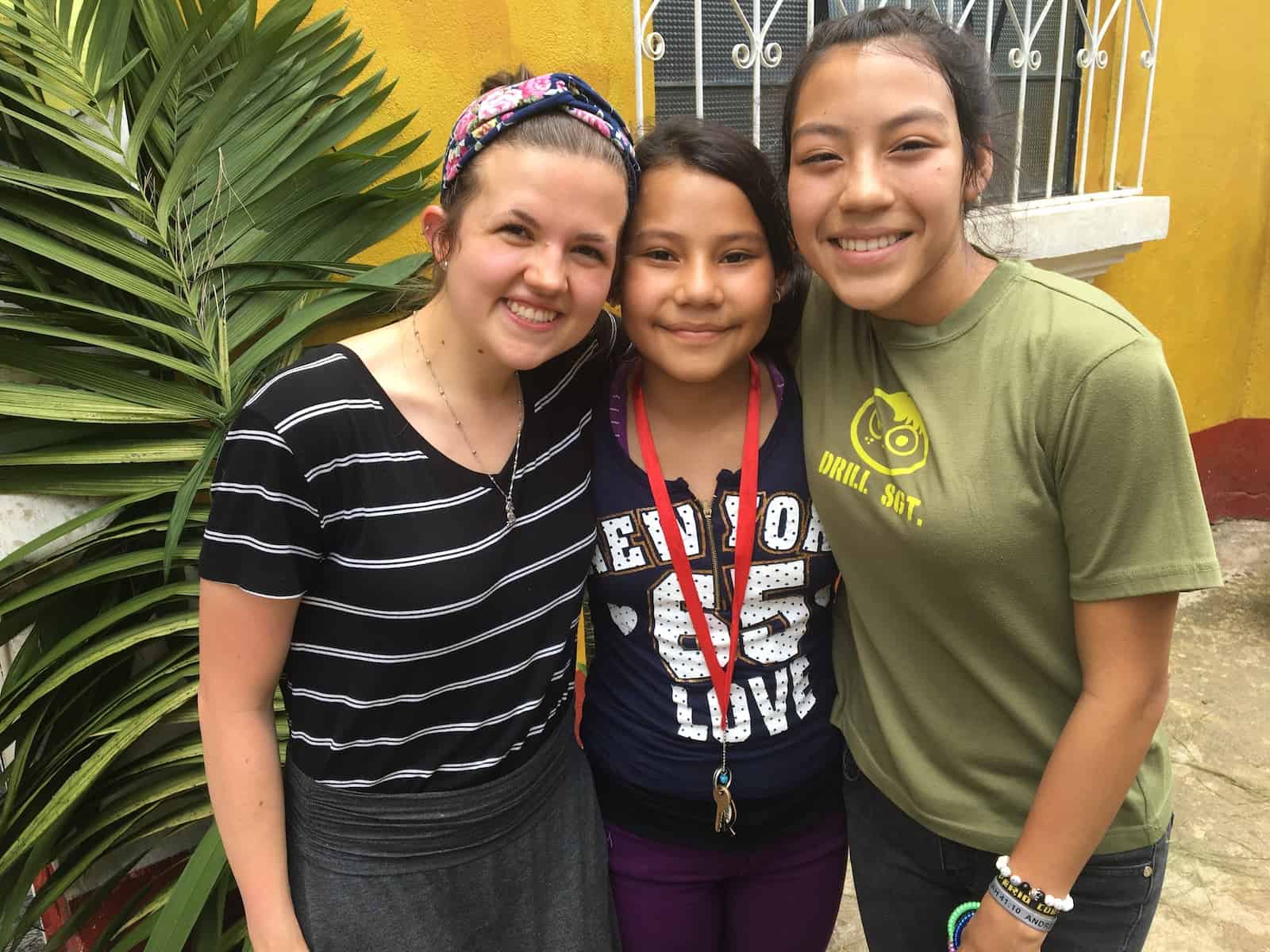 A young woman poses with two Guatemalan girls