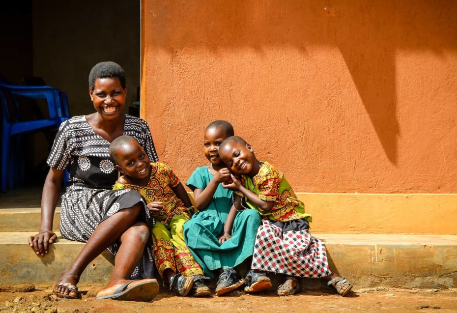 A woman and three children sit in front of an orange wall.