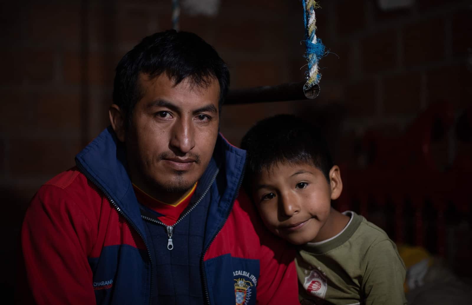 A man and boy sit next to each other in a dark room.