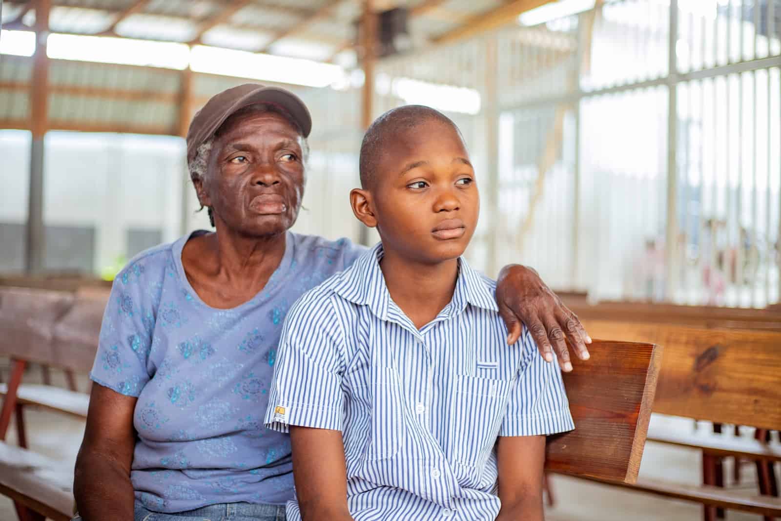 A boy and his grandma sit on a pew of a church. 