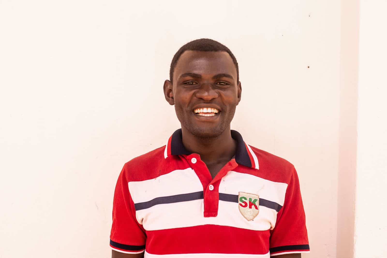 A man in a red and white striped shirt smiles at the camera. 