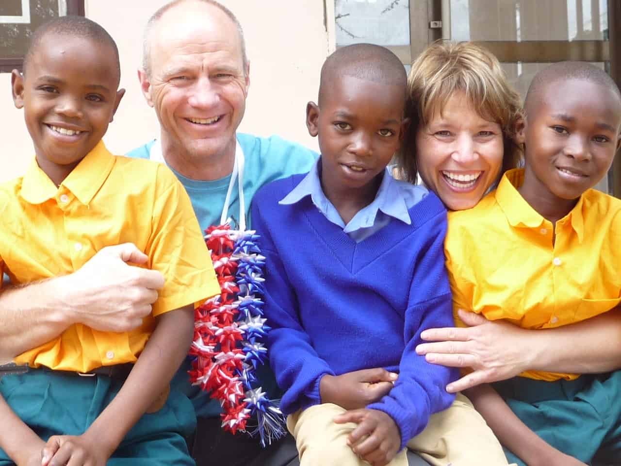 A man and woman hug three children in school uniforms