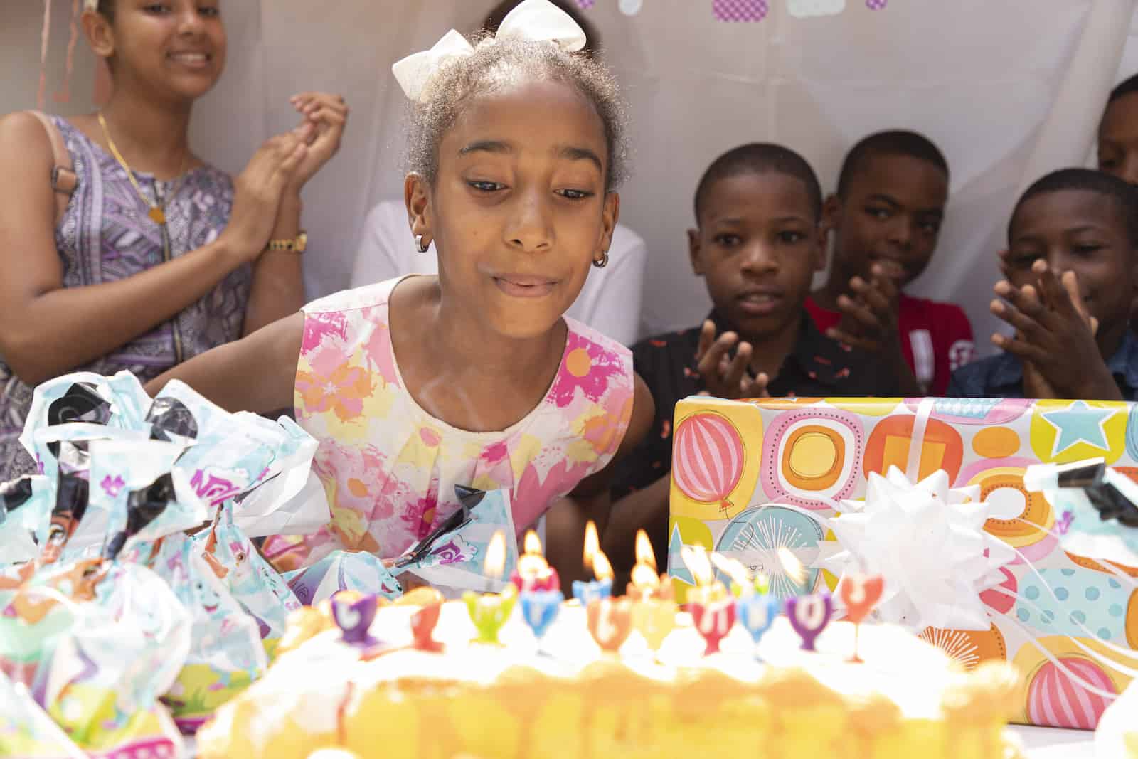 A girl leans over a birthday cake, blowing out the candles.