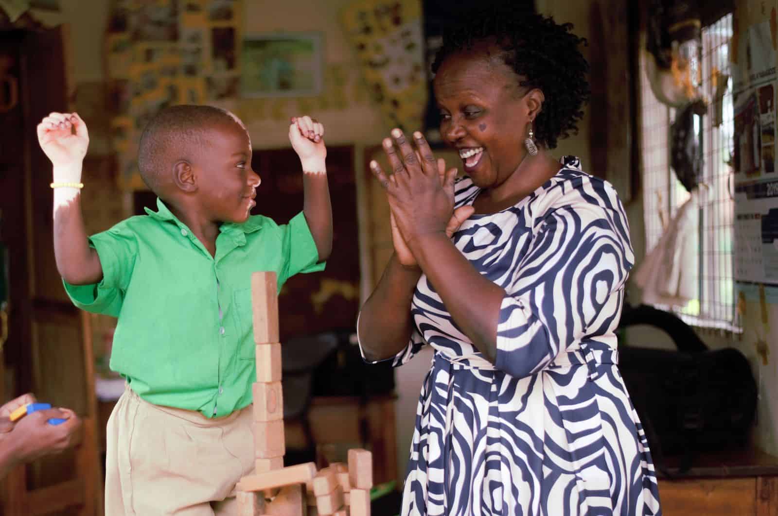 Waardenburg syndrome pictures - a boy with partial albinism puts his hands in the air while a woman claps for him.