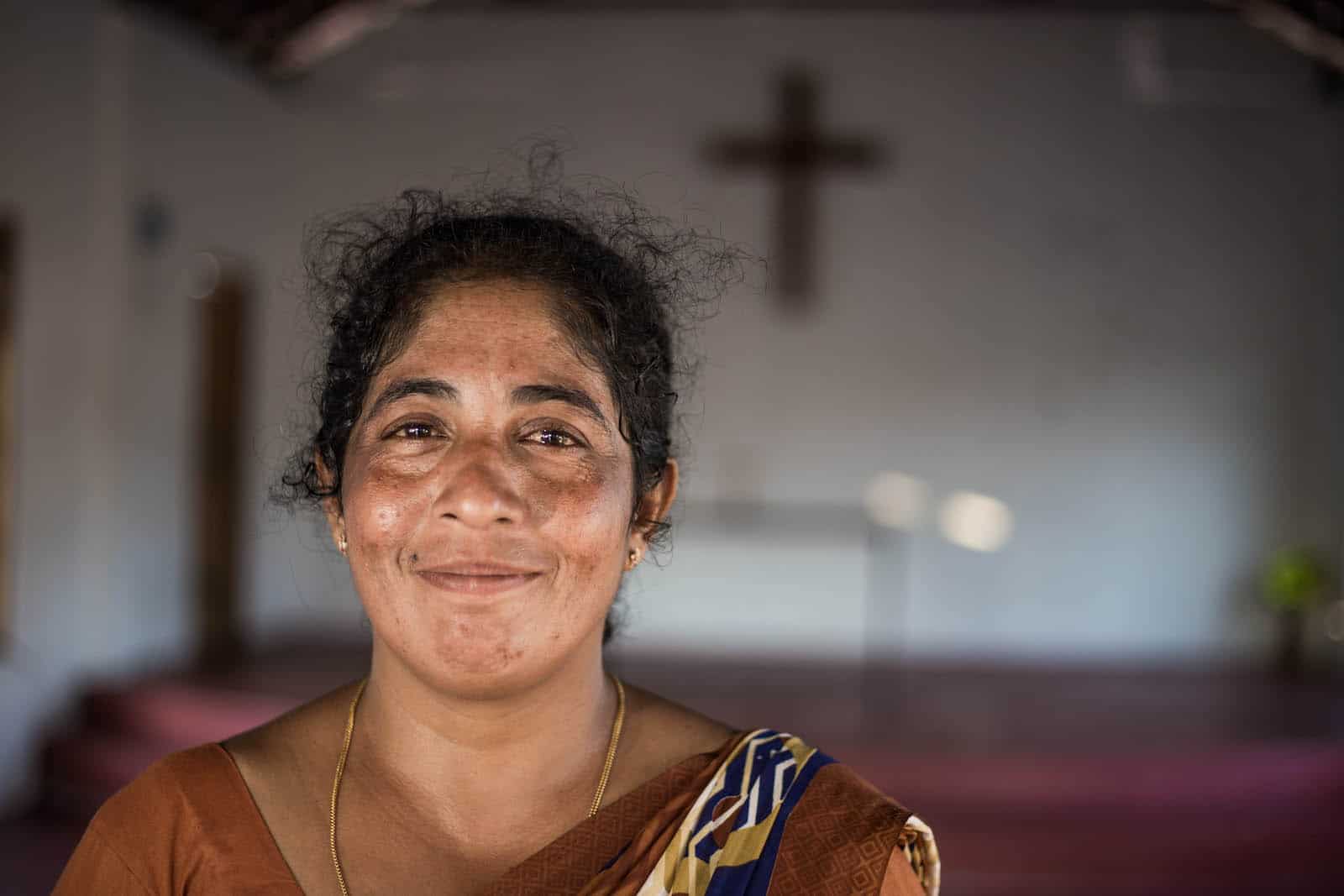 Victoria A woman who fights maternal suicide wears a brown dress standing in a church.