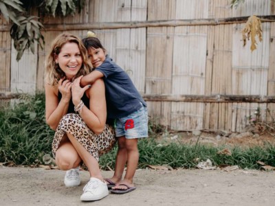 Candace Cameron Bure squats on the ground, with a young girl hugging her.