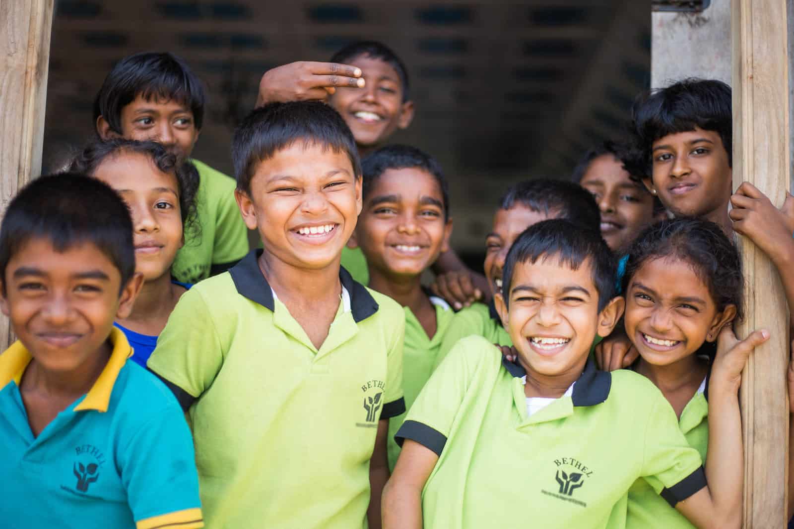 A group of children in lime green shirts smile at the camera.