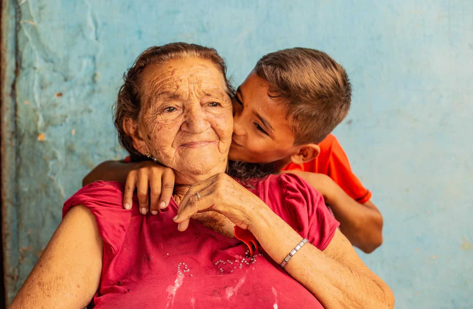 A boy kisses and elderly woman on the cheek.