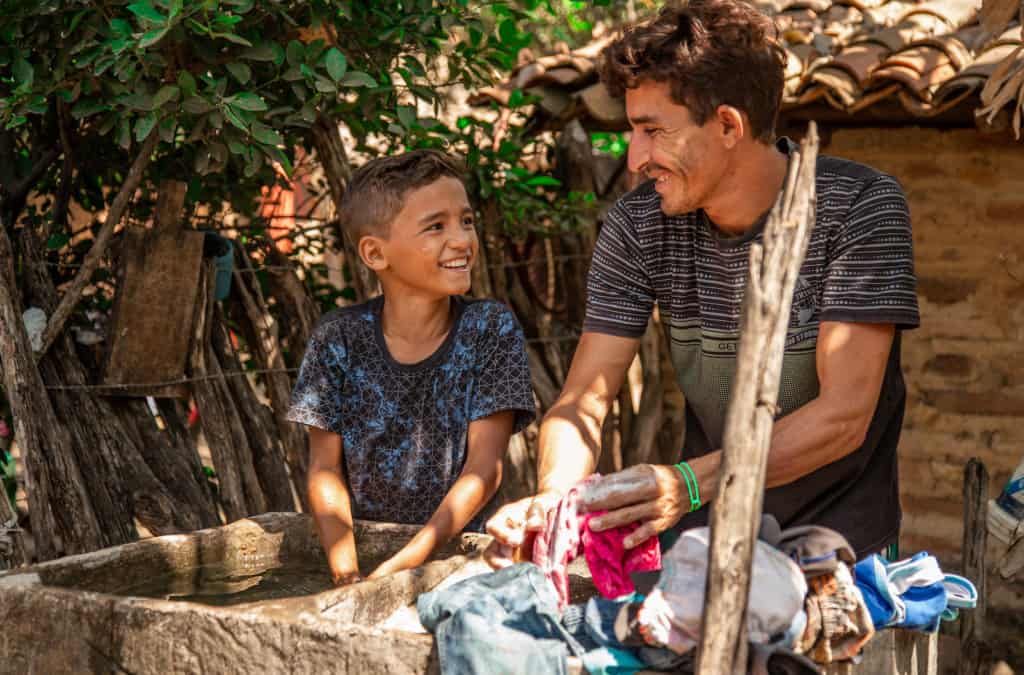 A boy and a man wash clothes outside together.