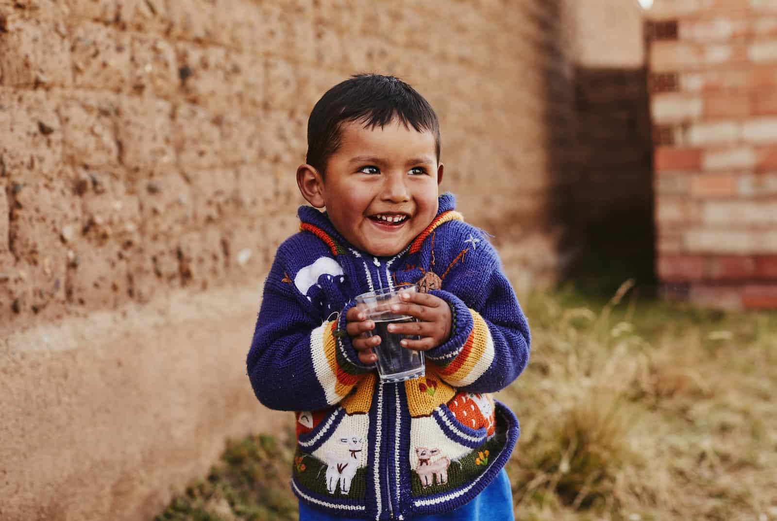 Kids Around the World: A boy in a blue sweater holds a glass of water.