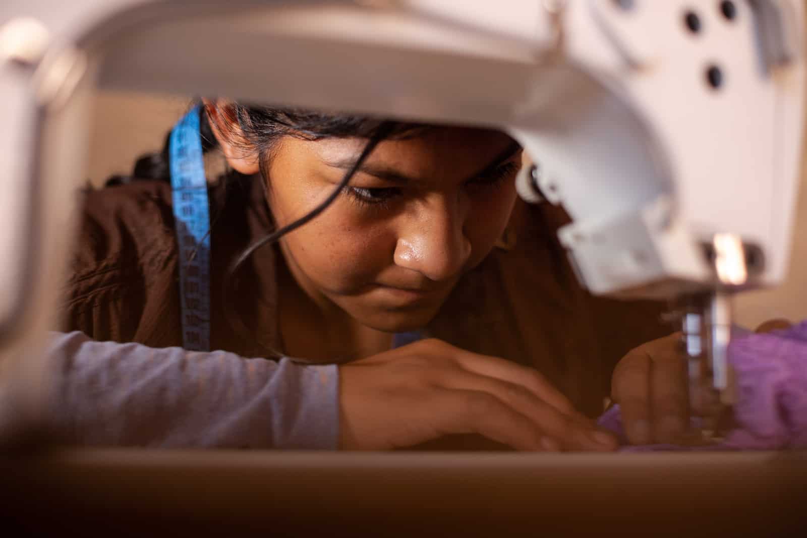 A girl sews at a sewing machine.