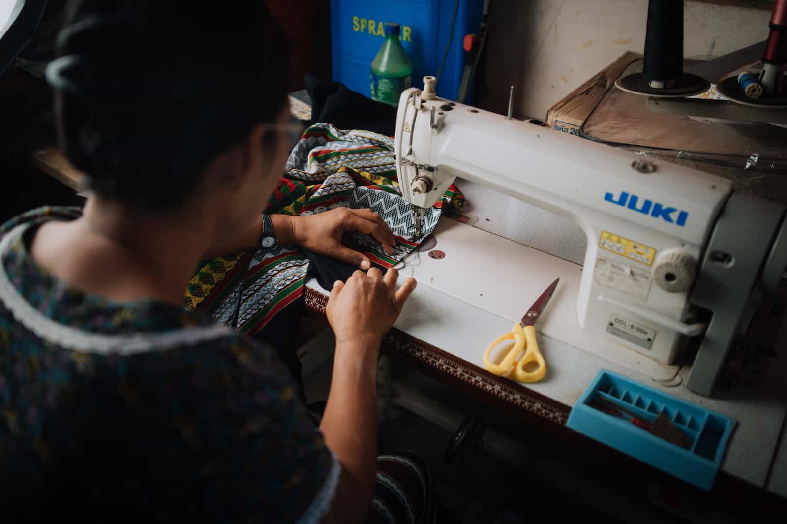 A woman sits at a sewing machine. 