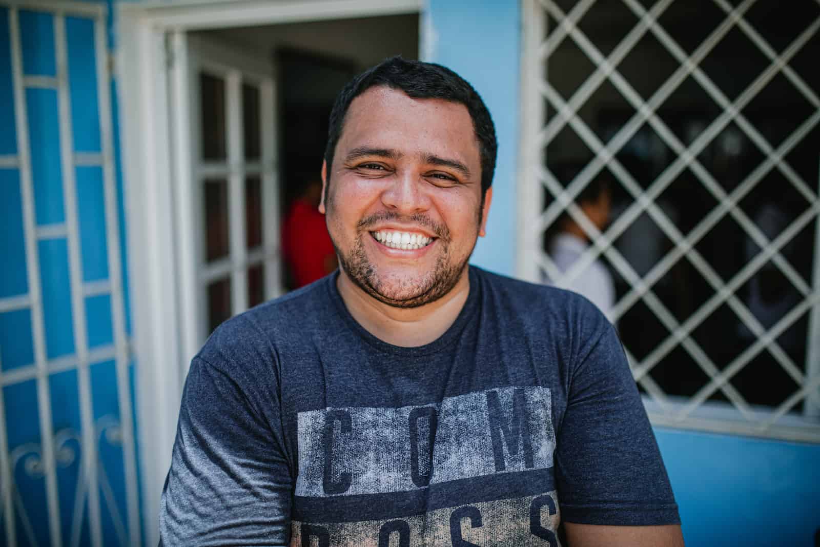 A man in a blue T-shirt smiles at the camera. 