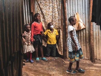 Four children stand in a slum in Kenya, where they are social distancing.