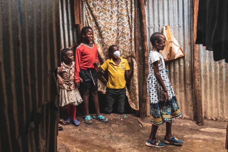 Four children stand in a slum in Kenya, where they are social distancing.