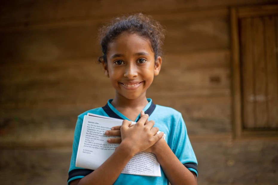 A girl hugs a letter to her chest.