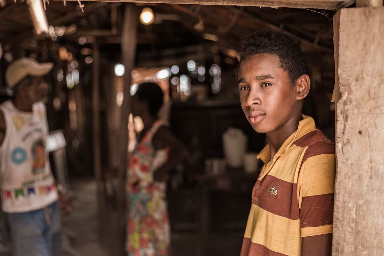 A boy stands at a door, looking out.