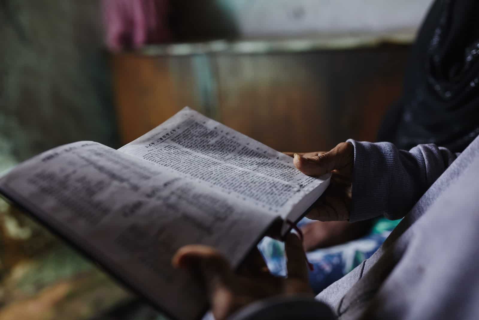 Hands hold an open Bible.