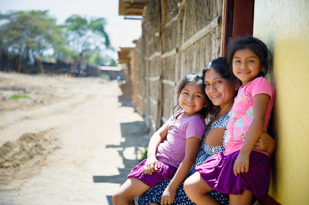 A happy mother and her children sitting by a wooden building