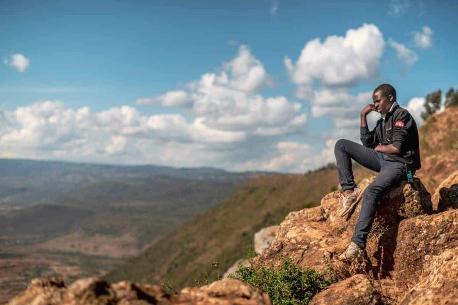 Boy sitting on an outcropping of rocks looking into the distance