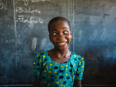 Girl from Togo in front of a chalkboard making a funny face