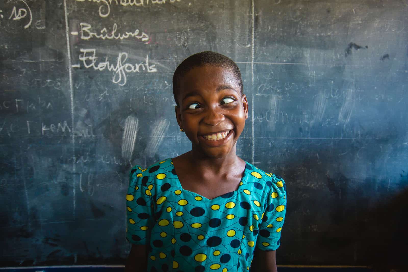 Girl from Togo in front of a chalkboard making a funny face