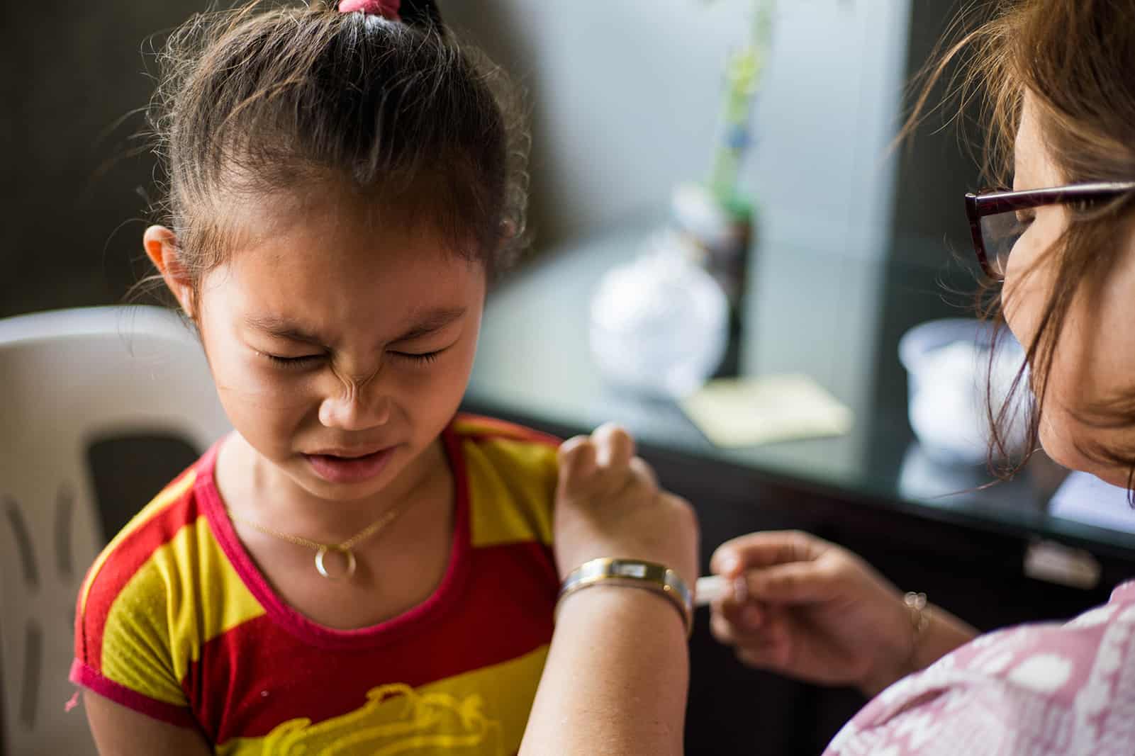 Girl wincing in pain while receiving a vaccination