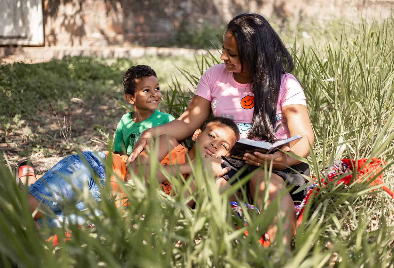 Mother and children reading in the grass