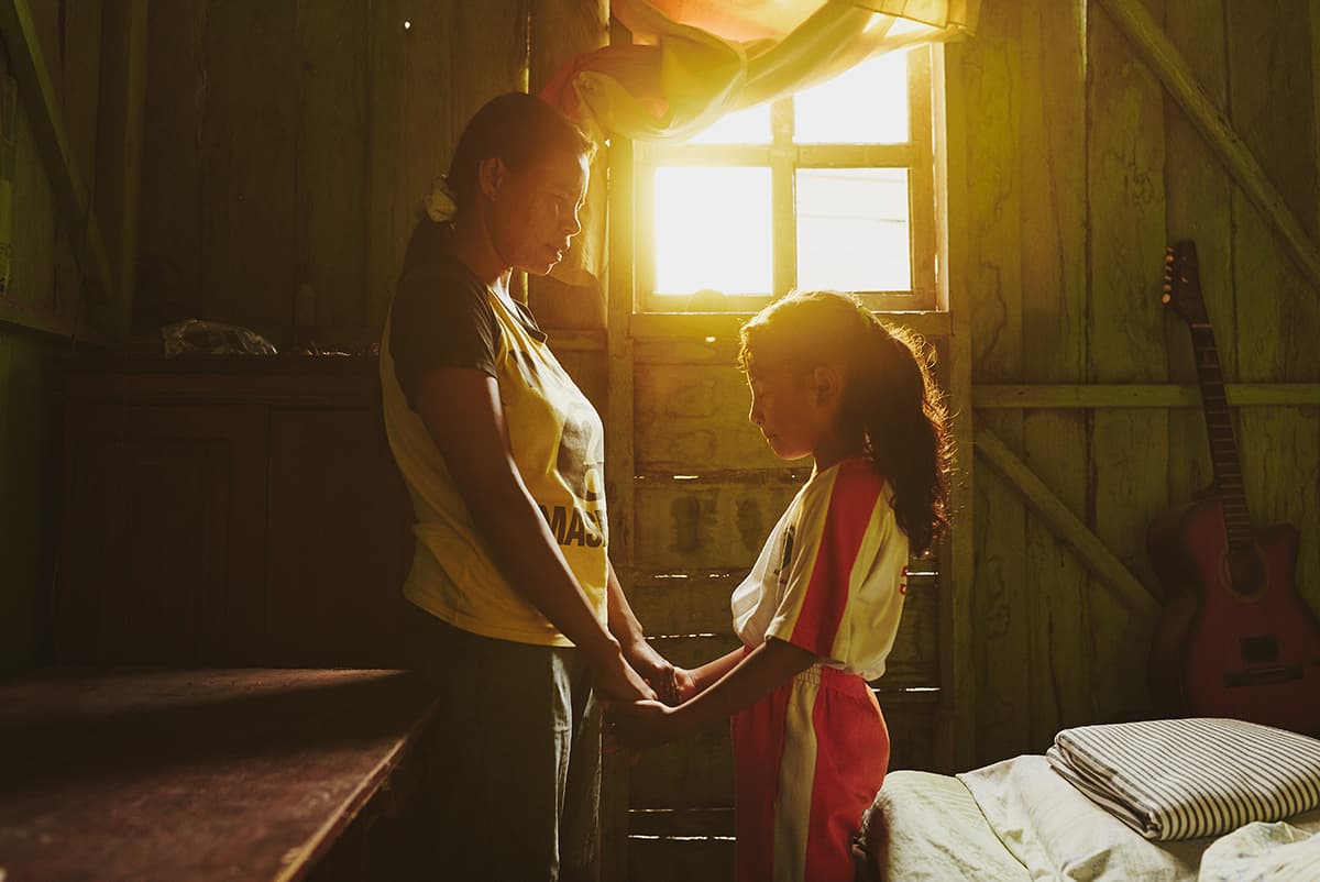 Mother and daughter holding hands praying