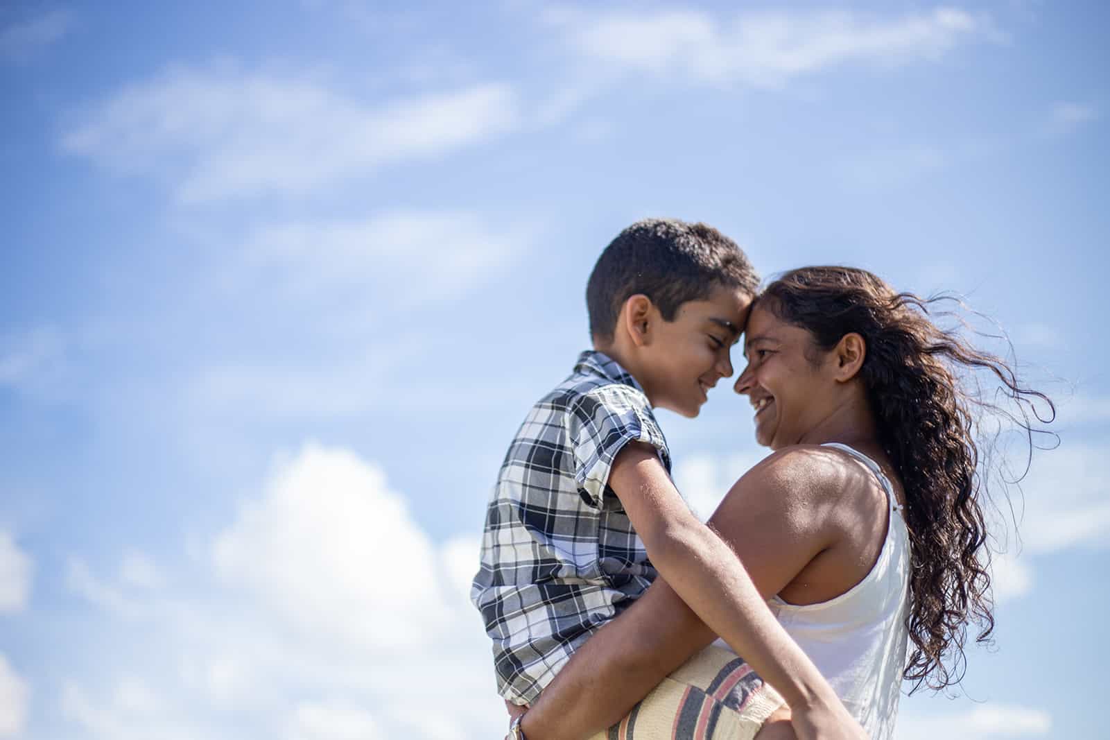 Mother looking lovingly at her son with the sky in the background